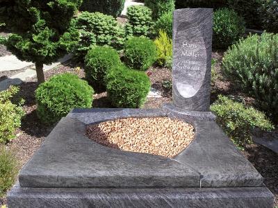 Urnengrab mit Einfassung und mehrteiliger Grababdeckung und ovalem Ausschnitt für Kiesfläche sowie Grabstein in Stelenform mit Inschrift